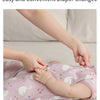 A hand is shown changing a baby diaper using a two-way zipper on a pink sleeping bag.