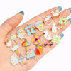 A hand displays various enamel marine life charms for jewelry making, including sea turtles, fish, and palm trees.