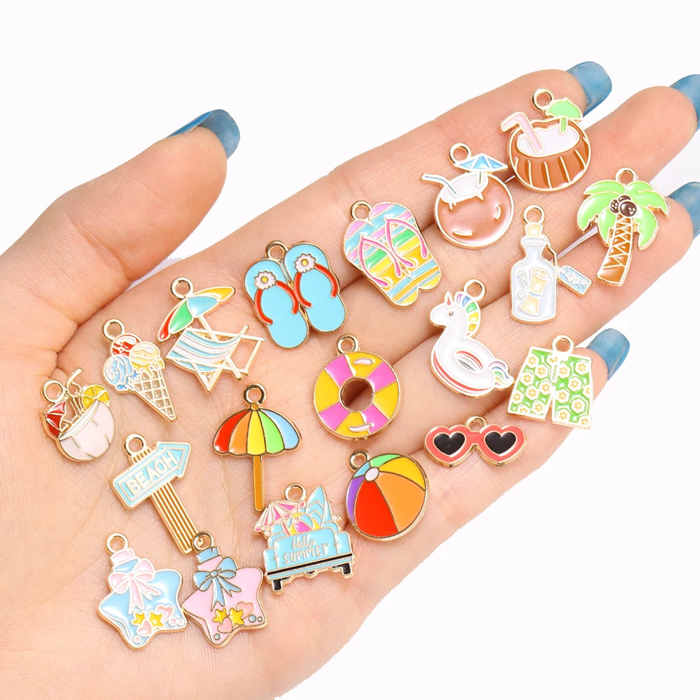 A hand displays various enamel marine life charms for jewelry making, including sea turtles, fish, and palm trees.