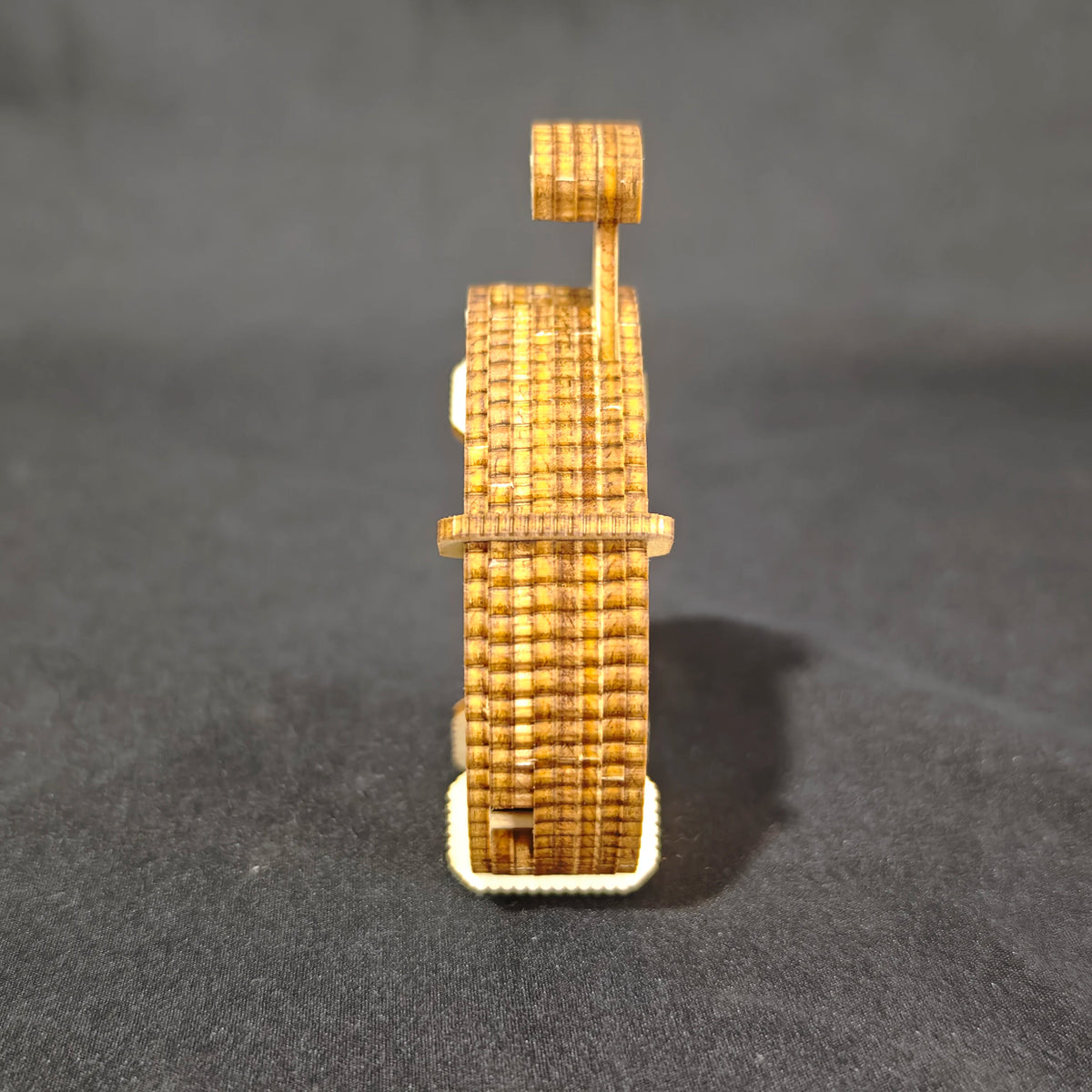 A small wooden dice puzzle kit model showing a vertical structure built from stacked, textured wooden pieces.