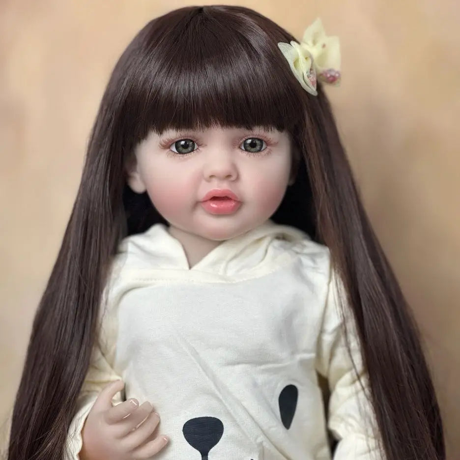 A lifelike 55 cm soft silicone baby doll with long dark hair and a white hooded top