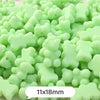 A pile of pastel green bear-shaped acrylic craft beads with a shimmer finish.