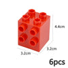 Un bloc de construction en plastique rouge avec six trous ronds sur la surface supérieure.