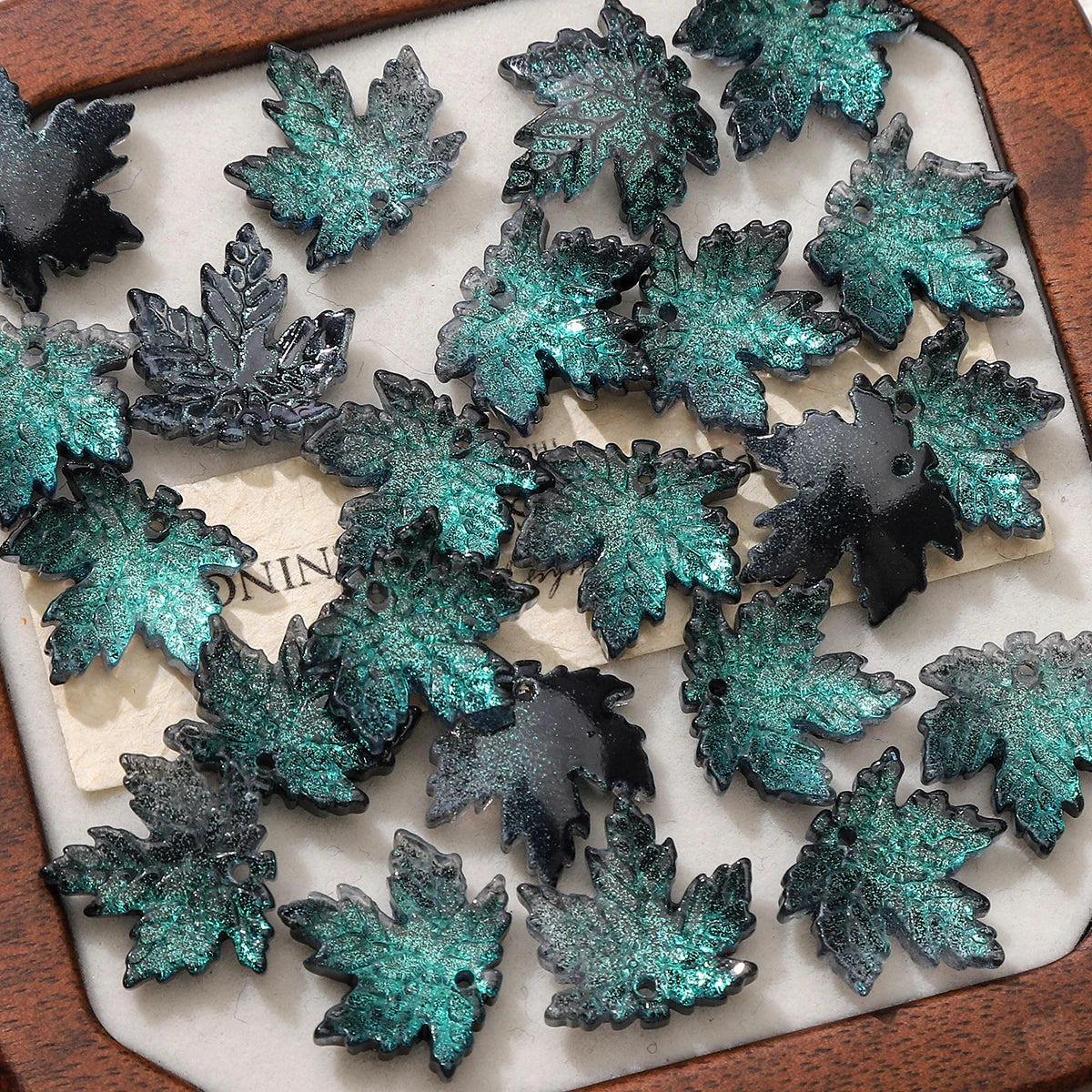 A collection of dark teal and black maple leaf glass beads for DIY jewelry making.
