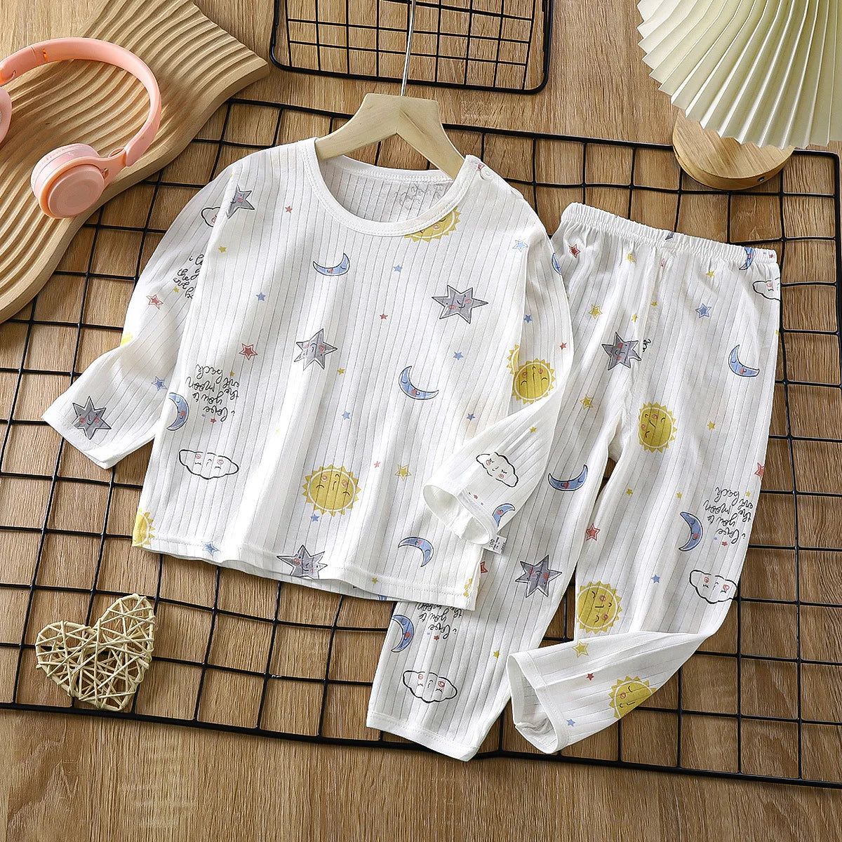 White long sleeve cotton pajama set for kids featuring a pattern of stars, moons, and suns