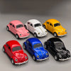 A collection of five classic retro Beetle diecast model cars in pink, white, yellow, red, and blue.