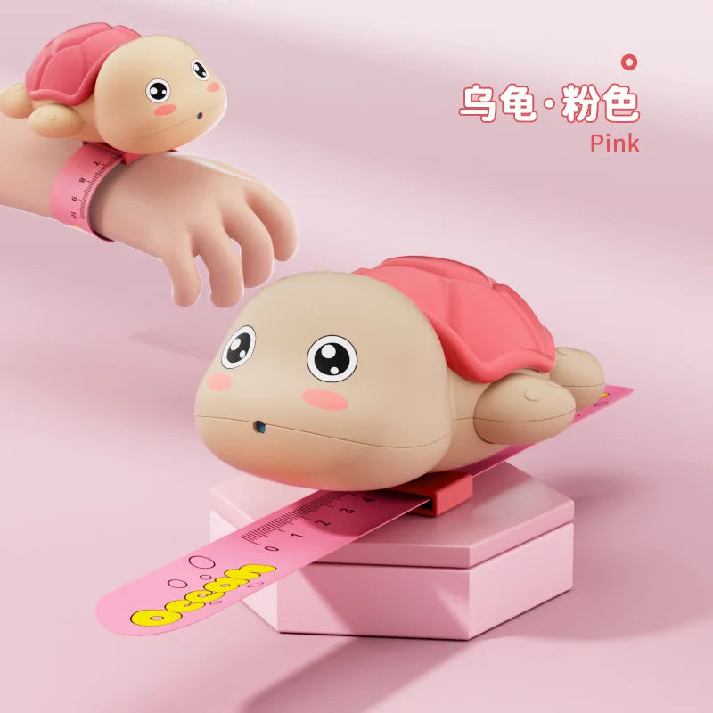 Pink turtle-shaped water gun with a pink hand and wristband shown in a studio setting.