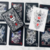A collection of black and white poker card decks featuring Hollow Knight artwork displayed on a white marble surface.