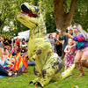 A person in a yellow inflatable T-Rex costume is posing outdoors among a crowd of people.