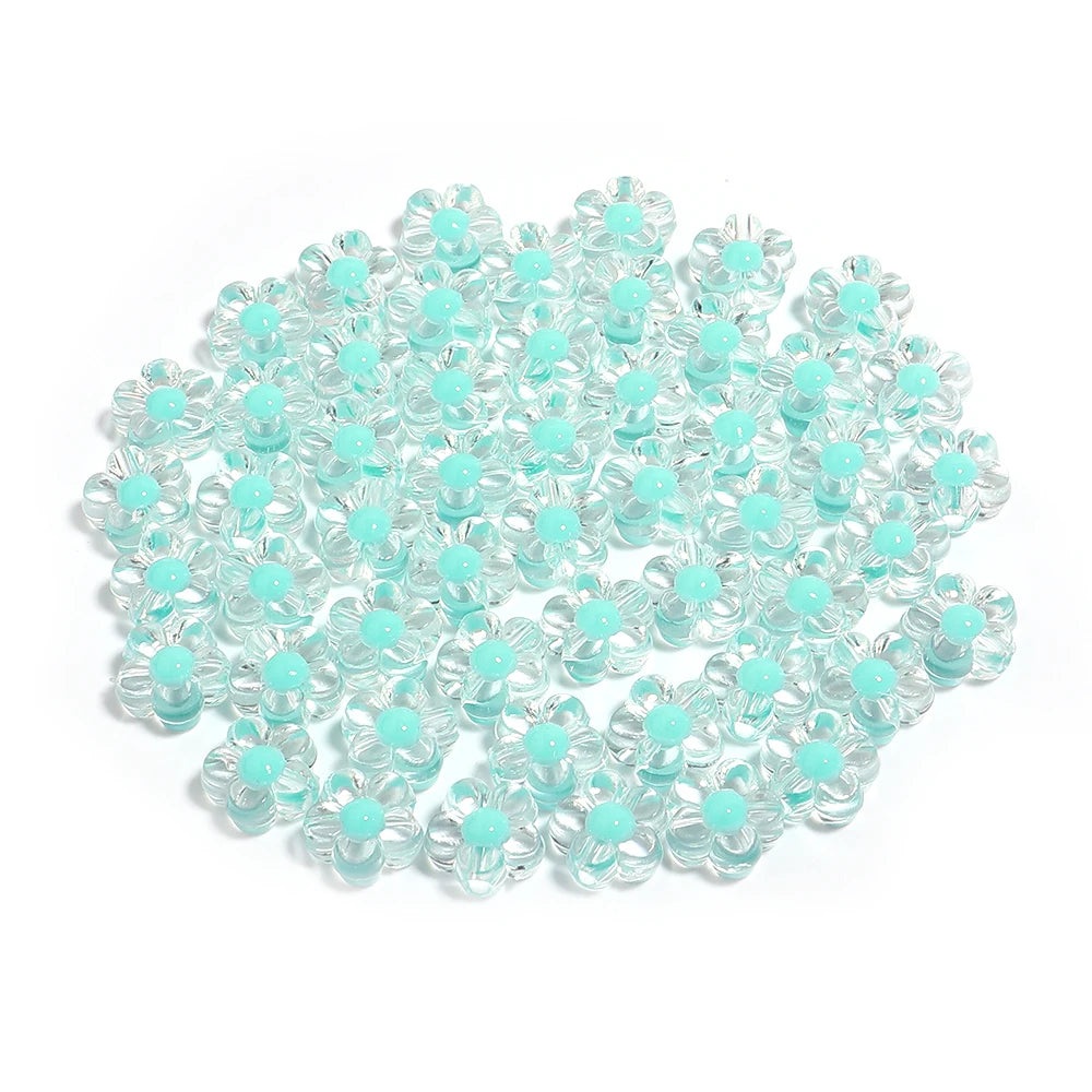 A pile of small, colorful transparent acrylic flower beads in various shades of light blue and teal.