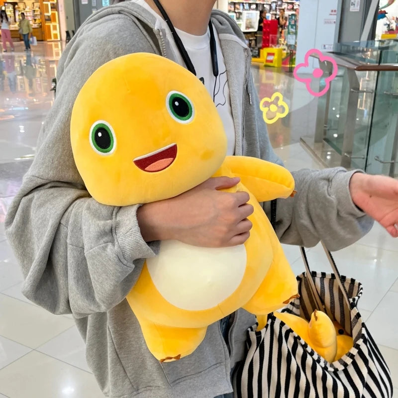 A person is holding a yellow Kawaii Milk Dragon plush pillow, a soft cute dinosaur stuffed animal, against a gray hoodie.