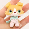 A miniature pet animal figure of a yellow dog with white markings and light green accessories being held in a hand.