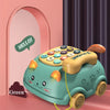 A green cat-shaped musical phone toy for toddlers with lights and sounds sitting on a pink surface.