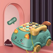 A green cat-shaped musical phone toy for toddlers with lights and sounds sitting on a pink surface.