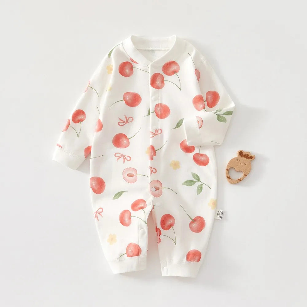 White cotton long sleeve baby romper featuring a pattern of red and green fruit leaves