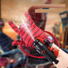 A hand wearing a red and black patterned glove is firing a stream of water from a wrist launcher.