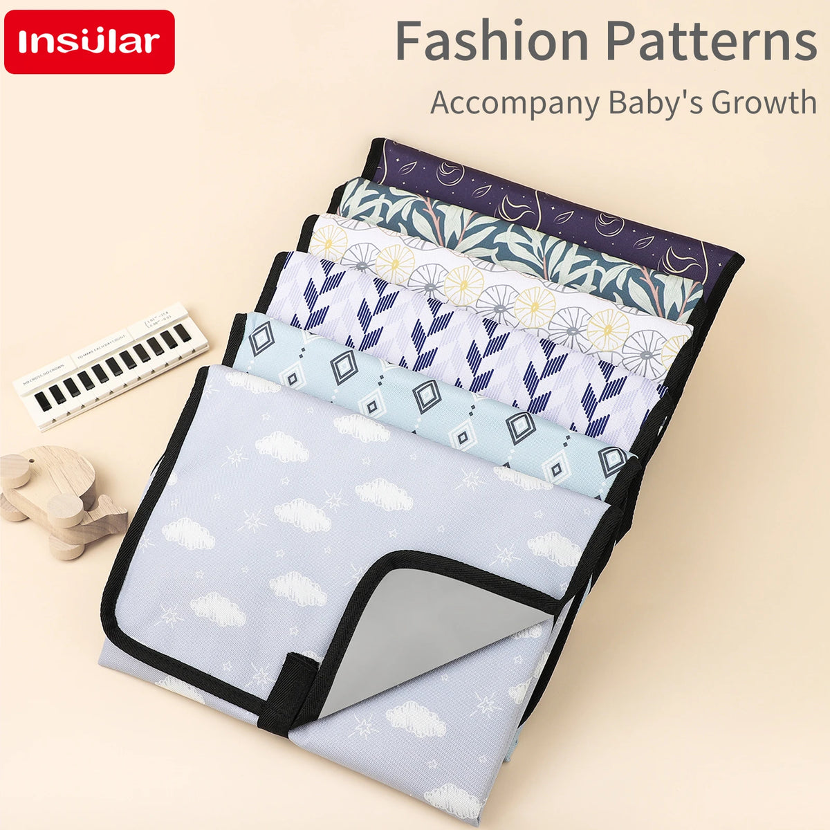 A stack of colorful fabric fashion patterns for a baby's growth accompanying a portable foldable waterproof diaper changing p