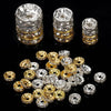 A collection of silver and gold crystal rondelle spacer beads for jewelry making displayed on a black surface.