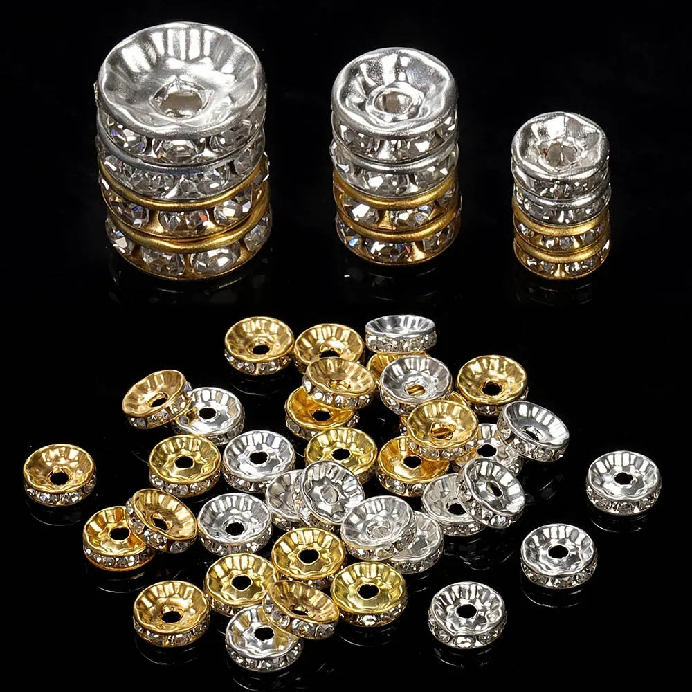 A collection of silver and gold crystal rondelle spacer beads for jewelry making displayed on a black surface.