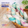 Spool of hand-dyed Australian wool yarn featuring a vibrant gradient mix of pink, blue, and green fibers.