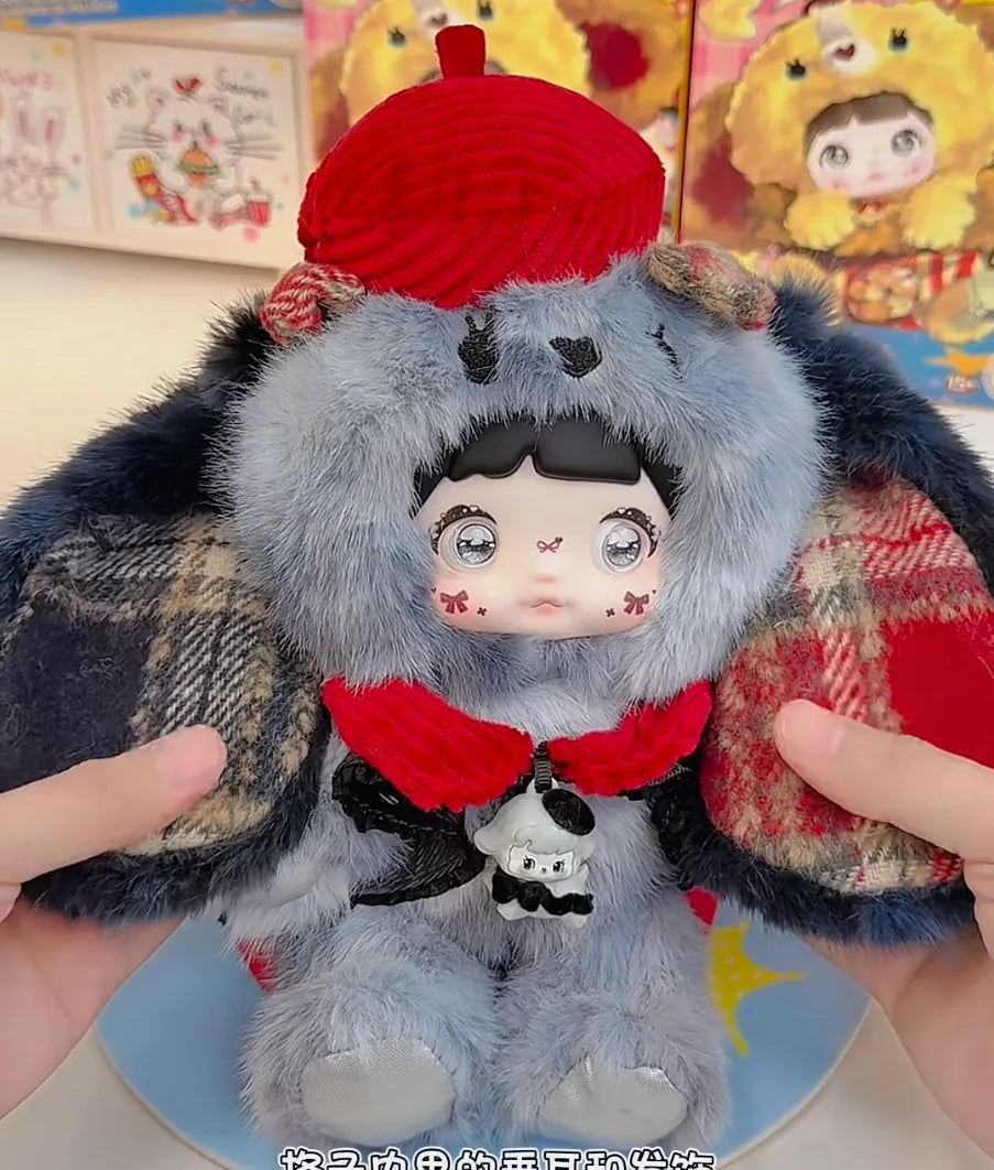 A fluffy gray and red collectible doll resembling a bear or animal, held by a hand.