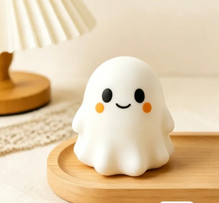 A white, squishy ghost-shaped stress ball rests on a wooden tray next to a lamp.