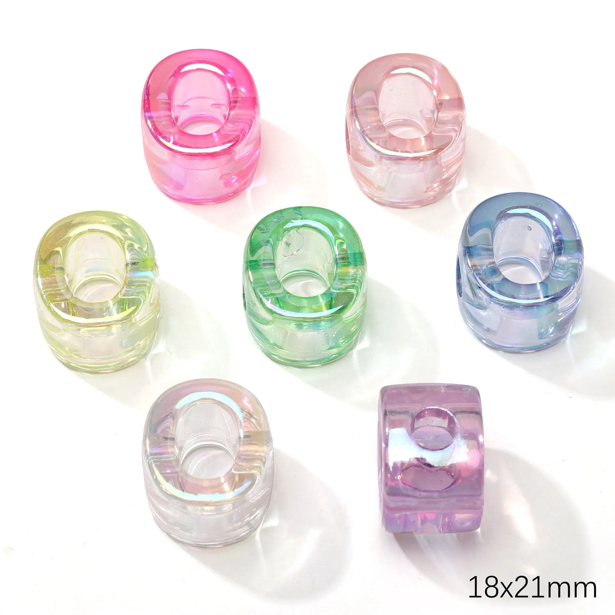A collection of colorful acrylic alphabet beads in pink, green, and blue shades displayed on a white background.