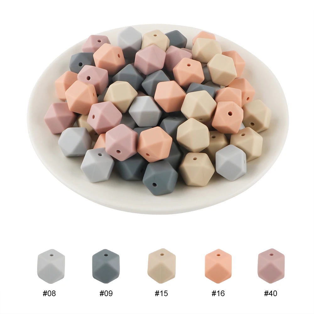 A collection of hexagonal silicone beads in various pastel and gray shades arranged on a white plate.