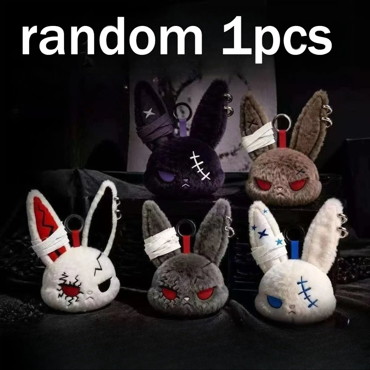 Three gothic bunny plush keychains with bandages and black ears displayed on a dark surface.