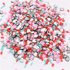 A pile of colorful polymer clay flower charms in various shapes and colors like pink, red, white, and blue.