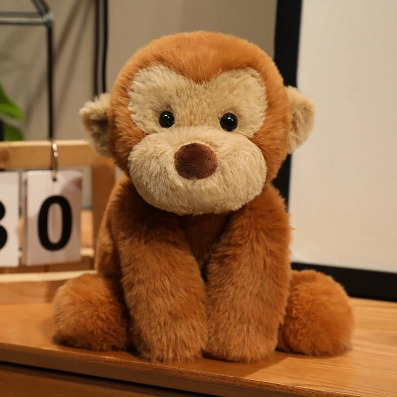 A fluffy, brown plush monkey soft toy sitting on a wooden surface.