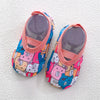 A pair of pink and blue patterned baby barefoot water shoes with pink straps.
