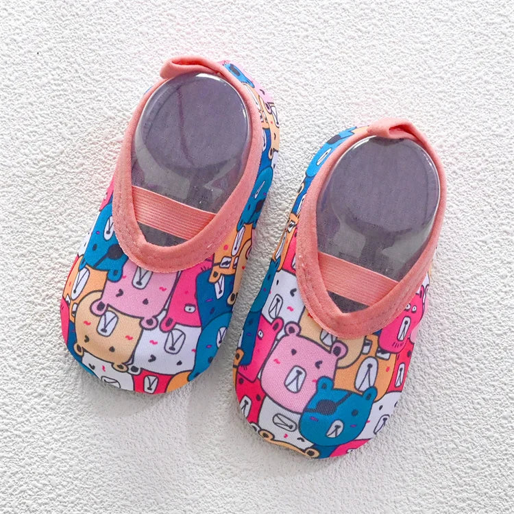 A pair of pink and blue patterned baby barefoot water shoes with pink straps.