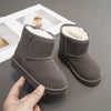A close-up of a gray fur-lined winter boot being held, showing the slip-on style and fuzzy lining.