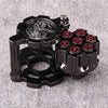 A black revolver-shaped metal dice set with numbered dice and a spinner on a gray surface.
