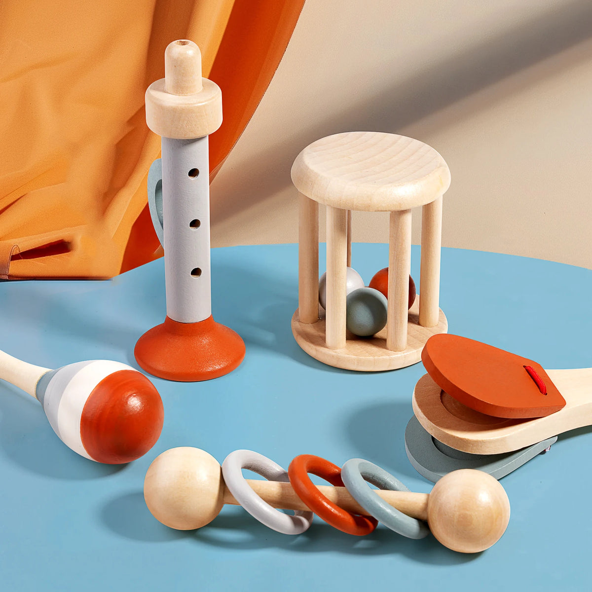 A collection of wooden hand bells and a wooden sensory toy stand on a blue surface.