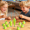 A fishing game with green plastic fish and fishing rods on a wooden table for children.