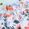White baby rash guard swimsuit with floral print featuring orange and blue leaves and a zipper detail.