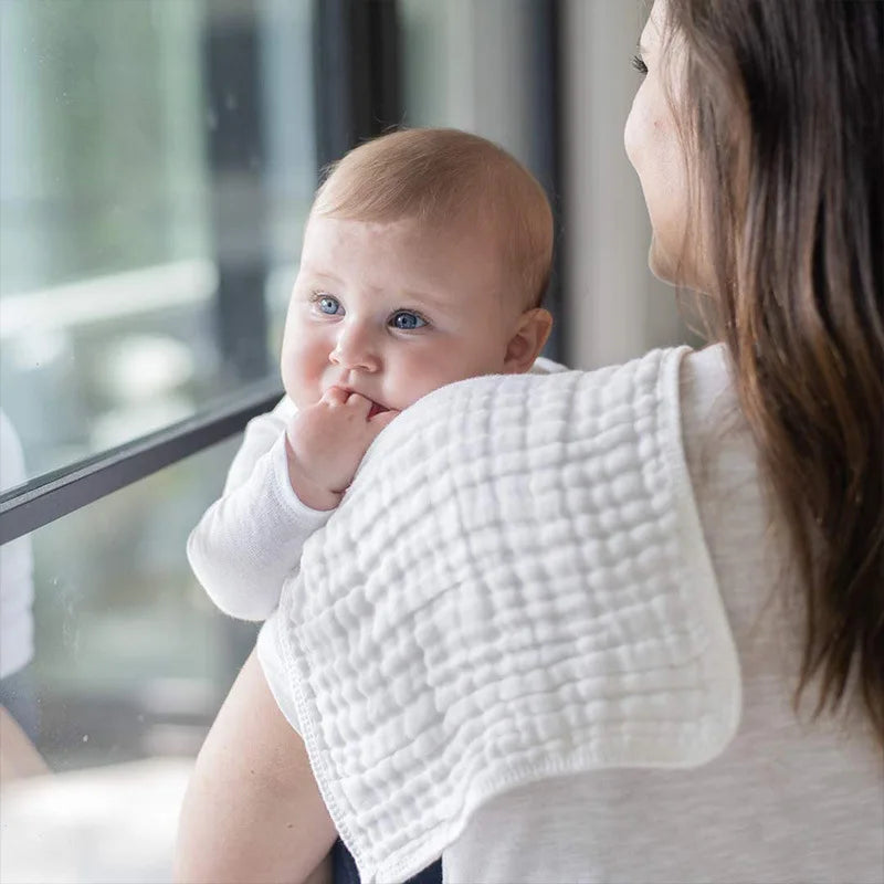 Eine Frau hält ein Baby und demonstriert oder benutzt ein Set aus drei weißen Baby-Schnuller.