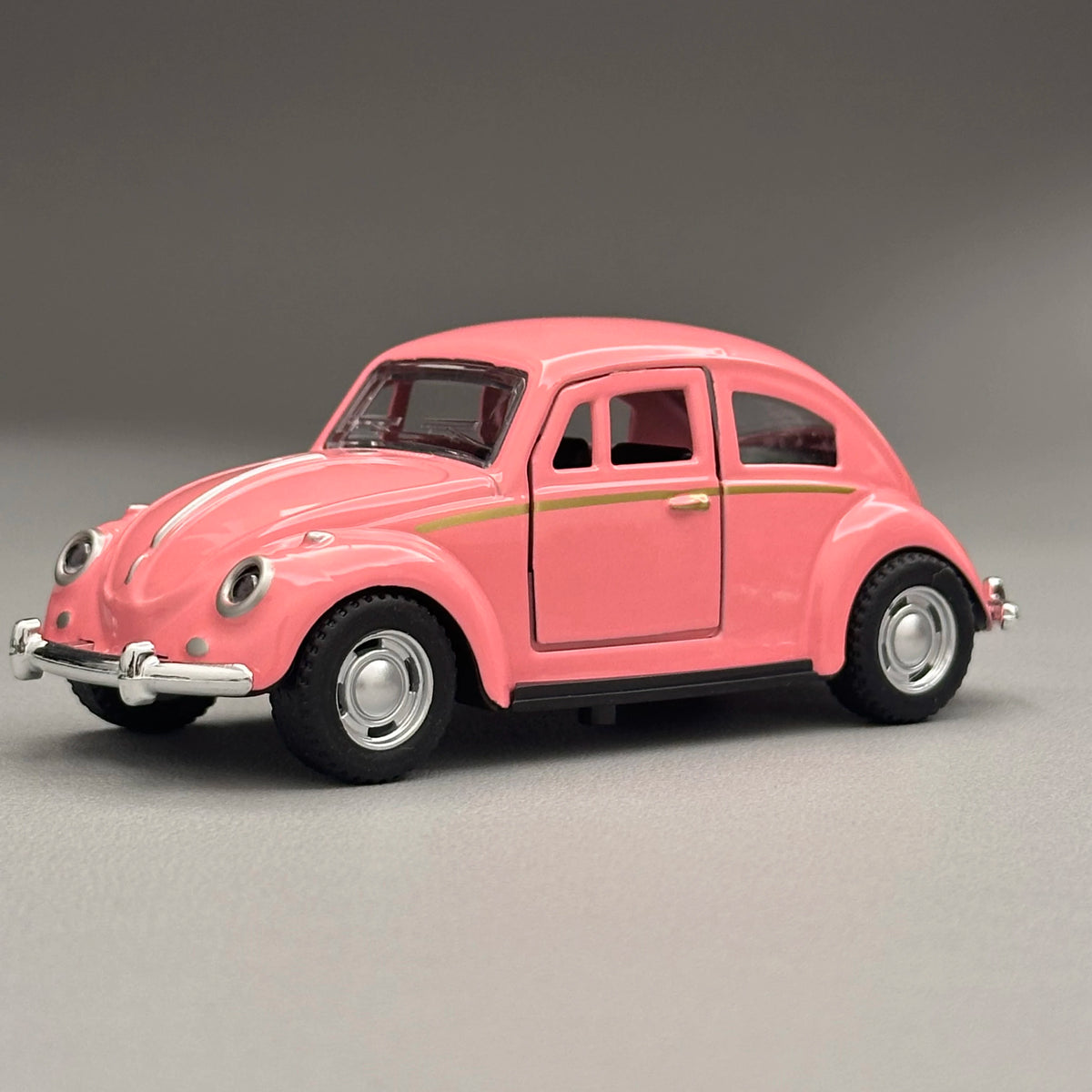 A pink classic retro Beetle diecast model car with gold trim, shown in a side profile.