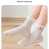 Pair of hand-sewn beige cotton socks with a floral trim shown on a foot.