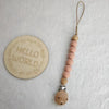 A wooden bead pacifier clip with silicone teether strung on a natural fiber cord.