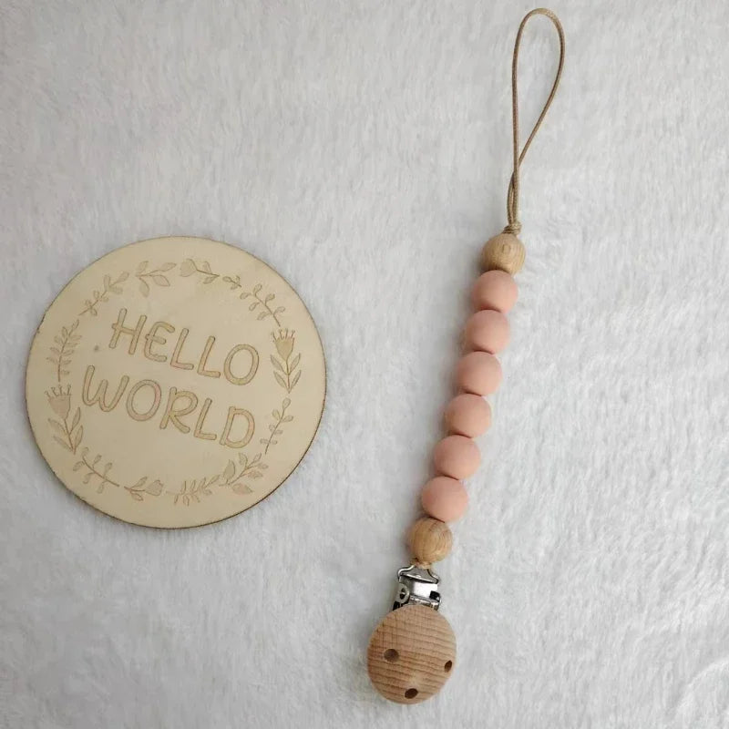 A wooden bead pacifier clip with silicone teether strung on a natural fiber cord.