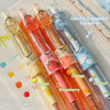A set of four colorful transparent pen barrels filled with fruit scents like Lemon, Strawberry, Orange, and Coconut.