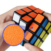 A hand holds an orange and black frosted magic cube puzzle with a blue magnified view of the orange surface.