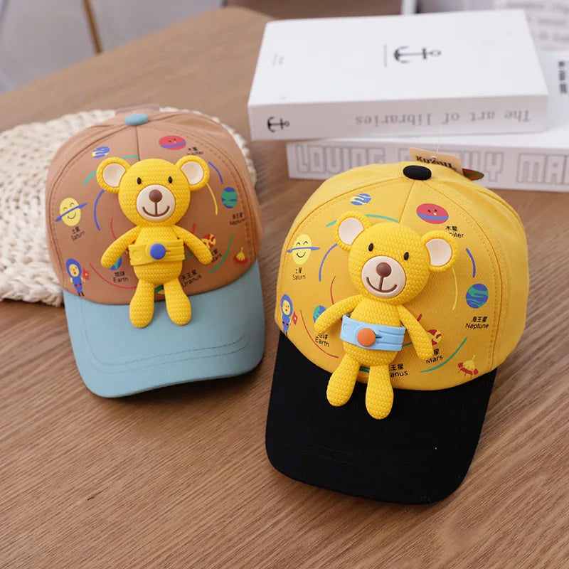 A yellow toddler bear baseball cap featuring a 3D embroidered bear design and an adjustable strap, resting on a wooden surfac