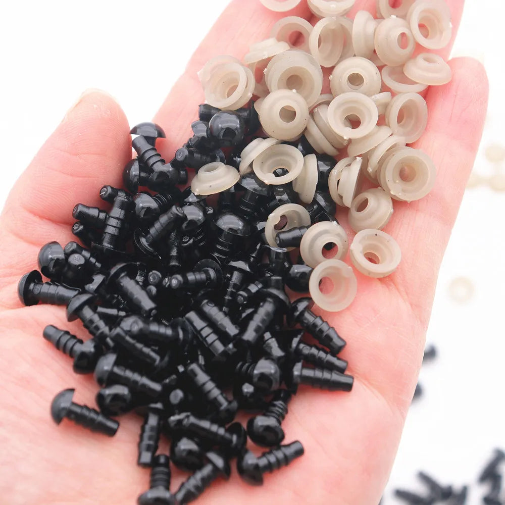 A hand holds a collection of black and beige plastic safety eyes for amigurumi with locking washers.
