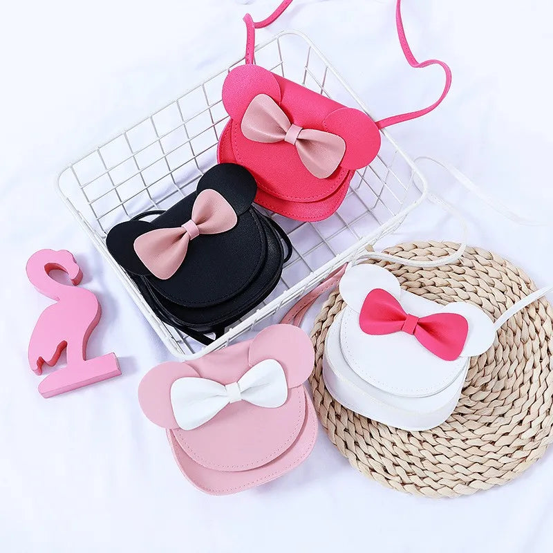 Pink and black kids hard shell crossbody bag with mouse ears and bow displayed on a white background.