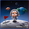 A collectible figurine of a boy in a spacesuit floating near the moon with a red flag.