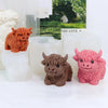 Three silicone molds of Highland cows in orange, brown, and pink colors displayed on white candles.